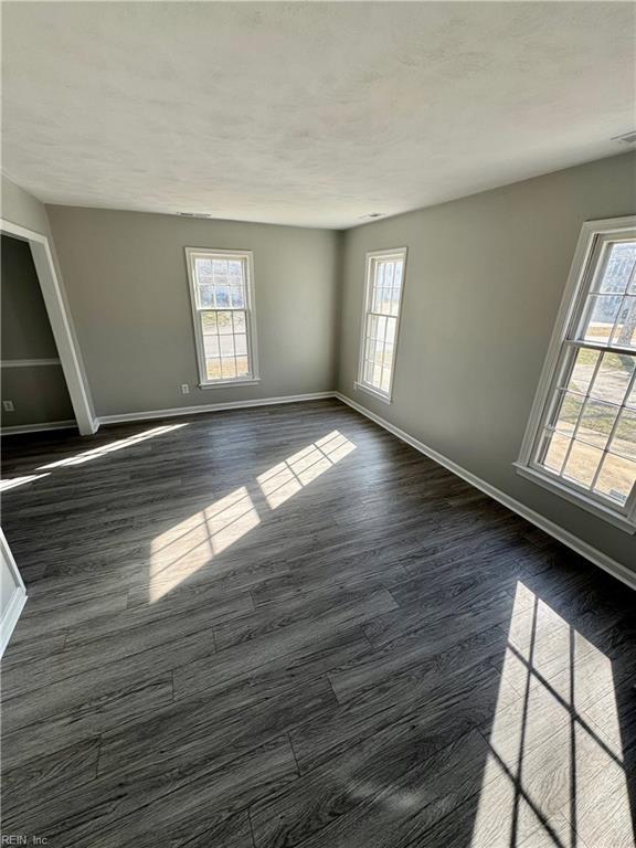 spare room with plenty of natural light, dark wood finished floors, and baseboards