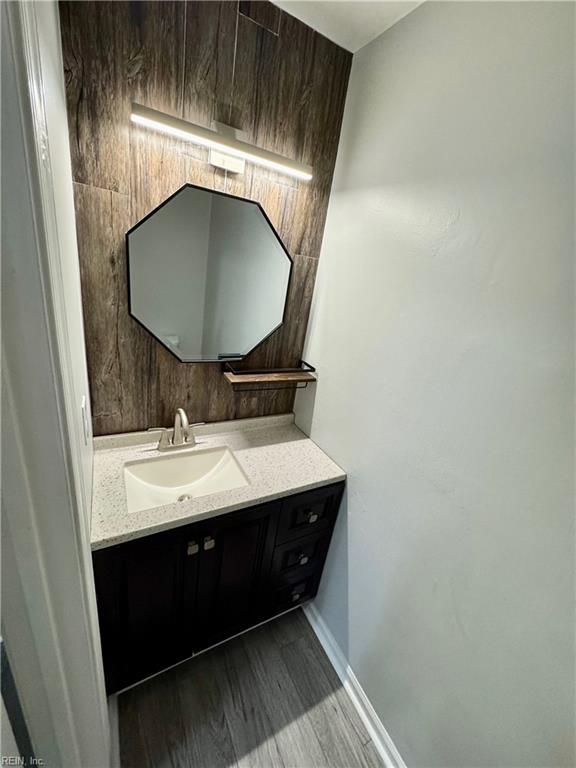 bathroom featuring baseboards, wood finished floors, and vanity