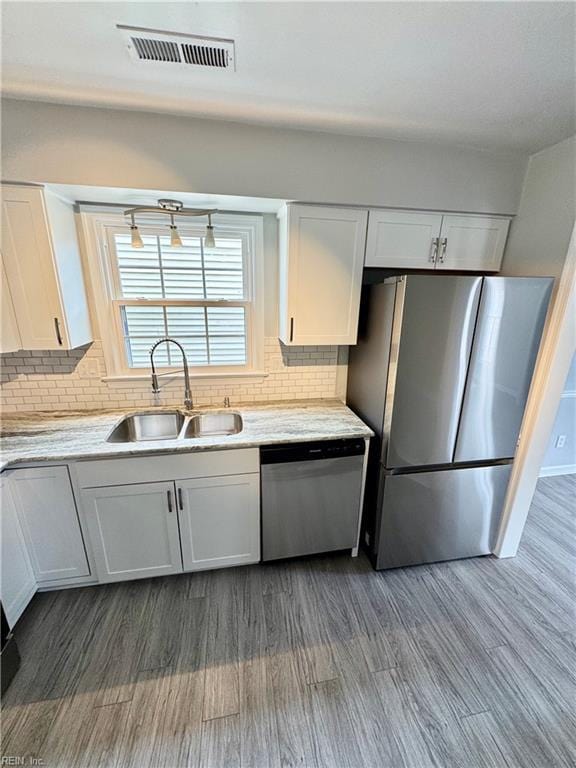 kitchen with dark wood-style flooring, visible vents, appliances with stainless steel finishes, white cabinetry, and a sink