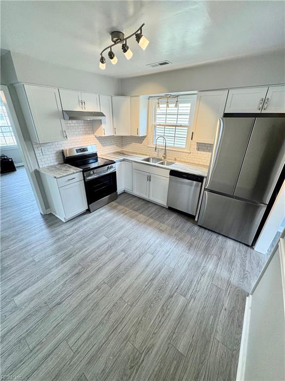 kitchen with stainless steel appliances, light countertops, visible vents, a sink, and under cabinet range hood