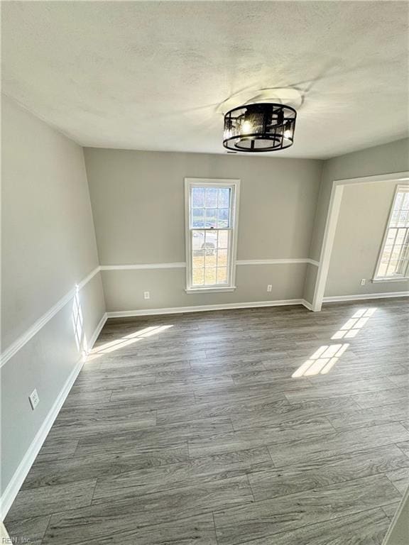 unfurnished dining area with a textured ceiling, baseboards, and dark wood-type flooring