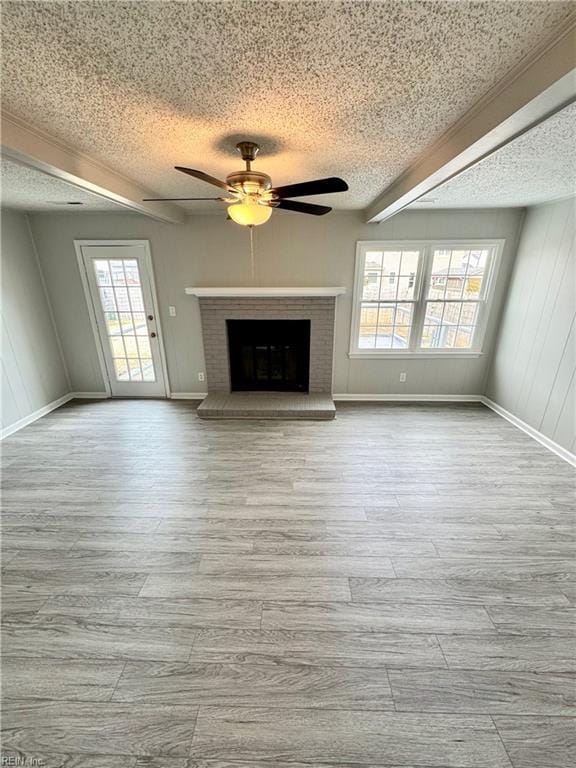 unfurnished living room with a textured ceiling, a fireplace, wood finished floors, and a ceiling fan