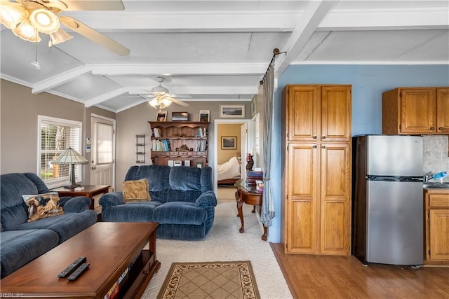 living area featuring vaulted ceiling with beams, light wood-style flooring, and ceiling fan