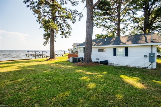 rear view of house featuring a water view, central air condition unit, and a lawn