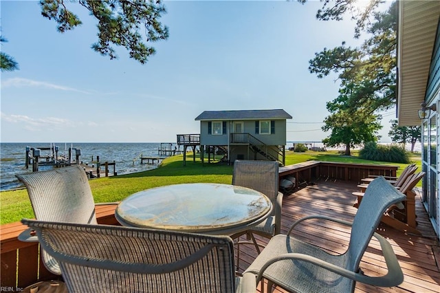 wooden terrace with a boat dock, boat lift, a water view, a yard, and outdoor dining space