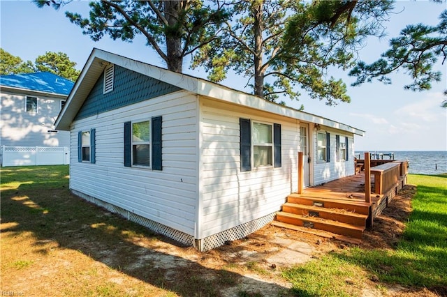 view of front facade with a front yard and a deck with water view