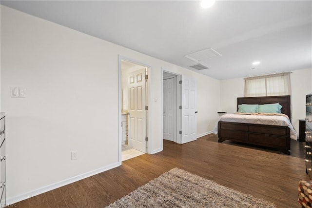 bedroom with attic access, visible vents, baseboards, and wood finished floors