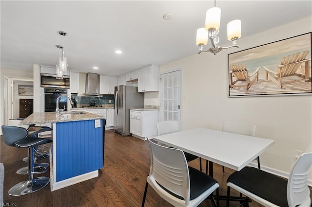 kitchen with stainless steel appliances, a sink, white cabinetry, wall chimney exhaust hood, and tasteful backsplash