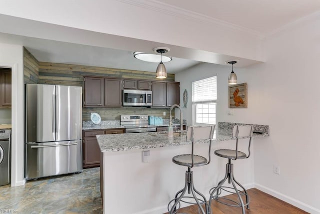 kitchen with crown molding, stainless steel appliances, washer / clothes dryer, a sink, and a peninsula