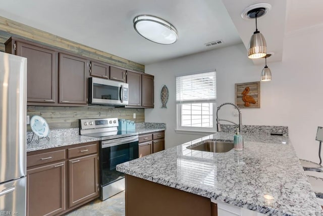 kitchen featuring stainless steel appliances, visible vents, decorative backsplash, a sink, and a peninsula