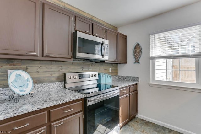 kitchen featuring light stone countertops, baseboards, stainless steel appliances, and decorative backsplash