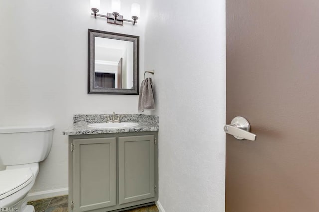 bathroom with vanity, toilet, and baseboards