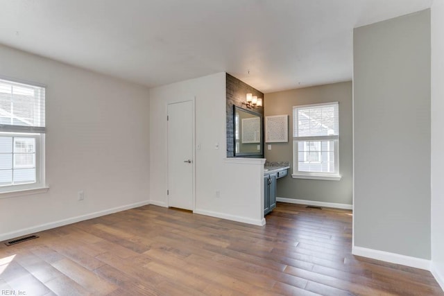 unfurnished room featuring wood finished floors, visible vents, and baseboards