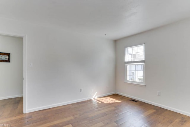 spare room featuring visible vents, baseboards, and wood finished floors