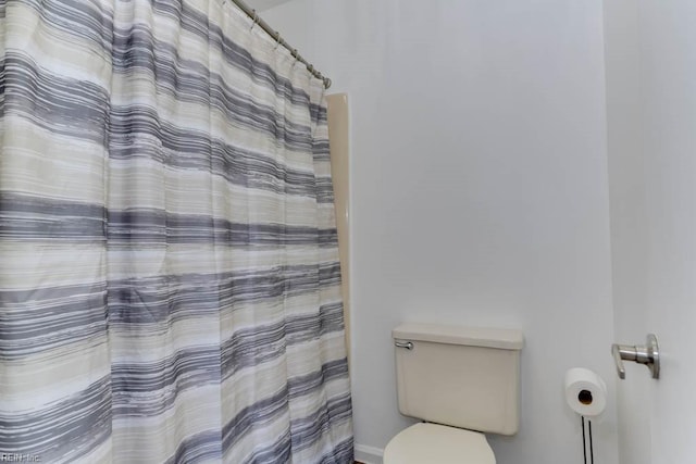 full bathroom with toilet and a shower with shower curtain