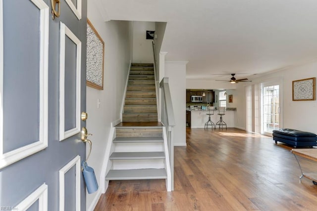 foyer entrance featuring ceiling fan, stairway, baseboards, and wood finished floors