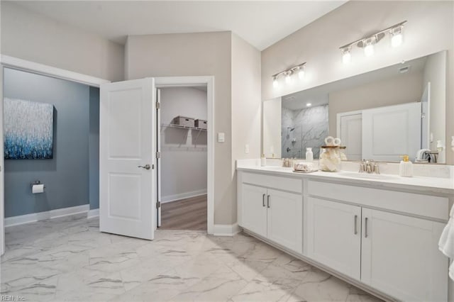 full bathroom featuring double vanity, baseboards, marble finish floor, walk in shower, and a sink