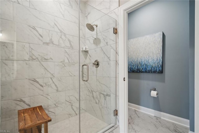 bathroom with marble finish floor, a stall shower, and baseboards