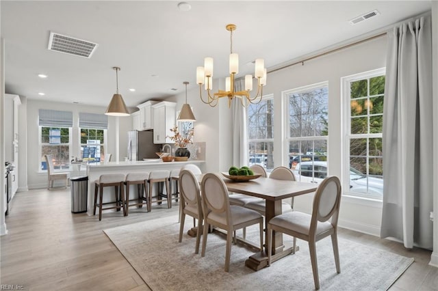 dining space with a notable chandelier, light wood-type flooring, visible vents, and recessed lighting