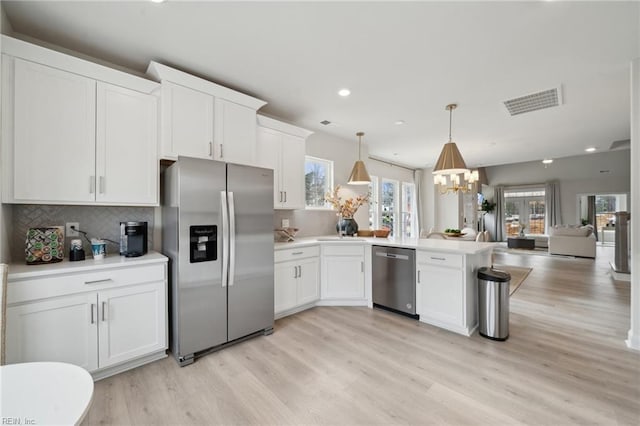 kitchen featuring visible vents, white cabinets, open floor plan, a peninsula, and stainless steel appliances