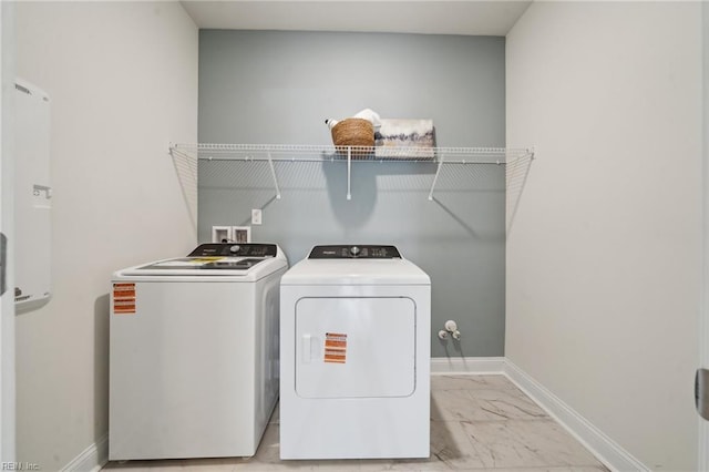 laundry room with laundry area, baseboards, marble finish floor, and washing machine and clothes dryer