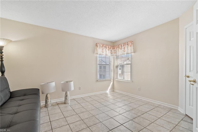 living area featuring a textured ceiling, baseboards, and light tile patterned floors