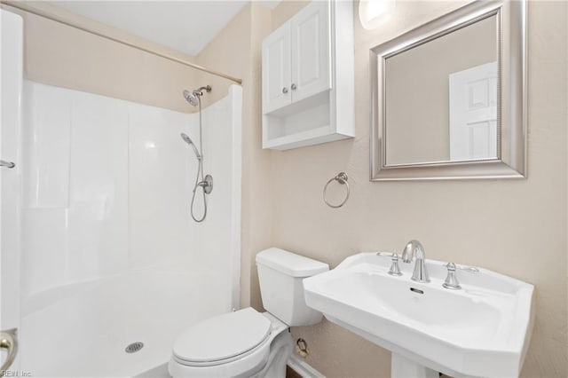 bathroom featuring a shower, a sink, and toilet