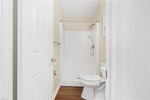 full bathroom featuring a shower, toilet, and wood finished floors