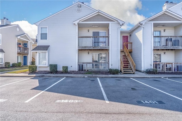 view of property featuring uncovered parking and stairs