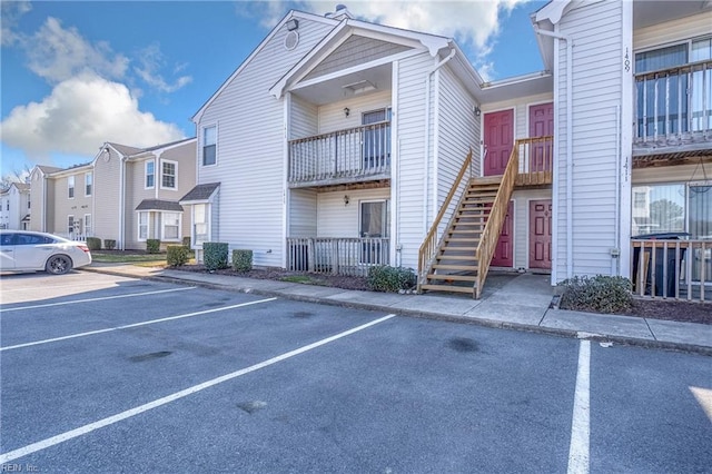 view of property featuring stairs, uncovered parking, a residential view, and central air condition unit