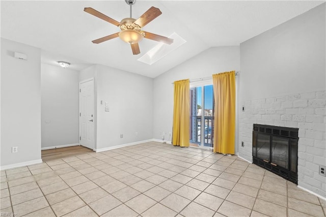 unfurnished living room with lofted ceiling with skylight, ceiling fan, a fireplace, and baseboards