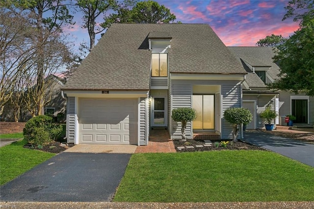 view of front of house with an attached garage, a shingled roof, aphalt driveway, and a front yard