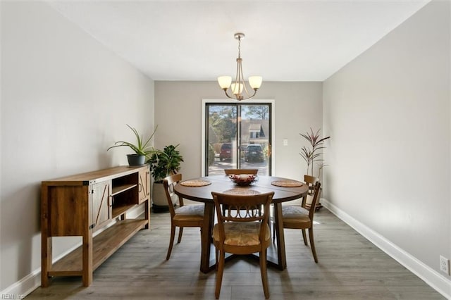 dining space with light wood-type flooring, baseboards, and a notable chandelier