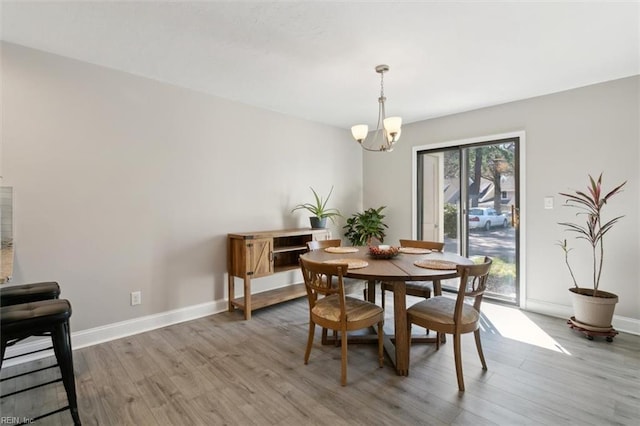 dining area featuring a notable chandelier, wood finished floors, and baseboards