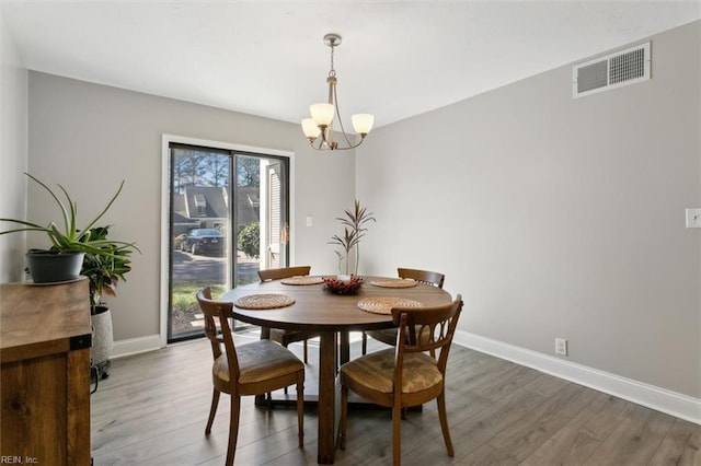 dining room featuring an inviting chandelier, visible vents, baseboards, and wood finished floors