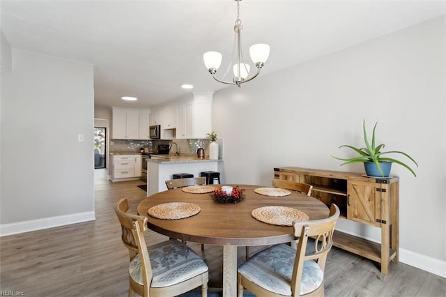 dining room featuring light wood-style floors, a notable chandelier, and baseboards