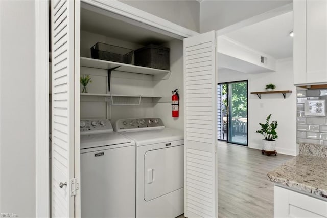 laundry room featuring laundry area, visible vents, ornamental molding, light wood-type flooring, and washing machine and clothes dryer