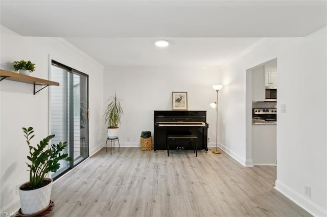 sitting room featuring light wood-style flooring, baseboards, and ornamental molding