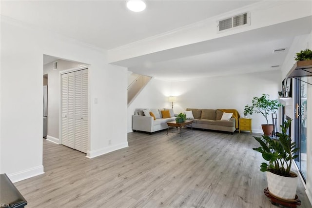 living room with baseboards, stairs, visible vents, and wood finished floors