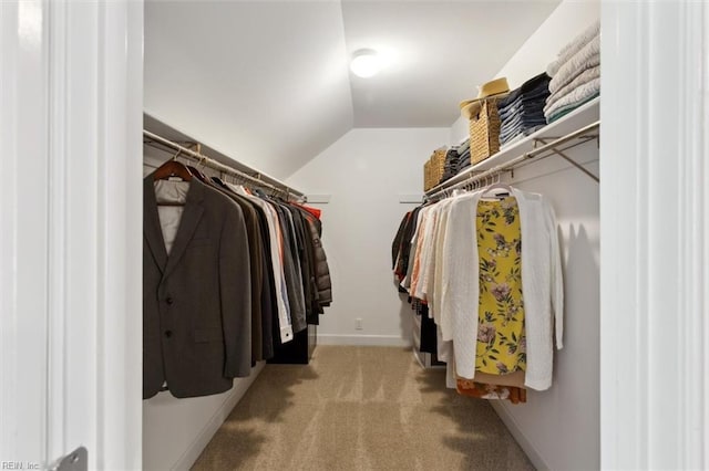 walk in closet with vaulted ceiling and carpet flooring