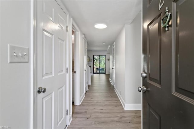 hallway featuring light wood-style floors and baseboards