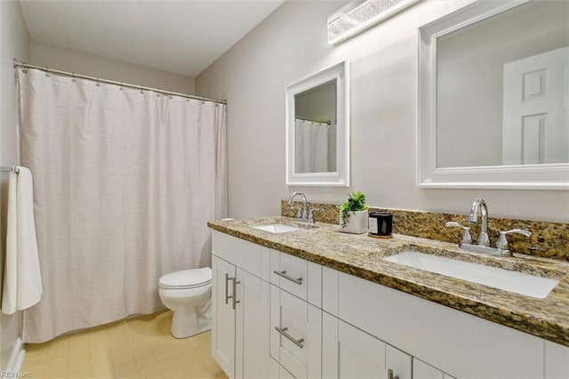 bathroom featuring toilet, double vanity, a sink, and tile patterned floors