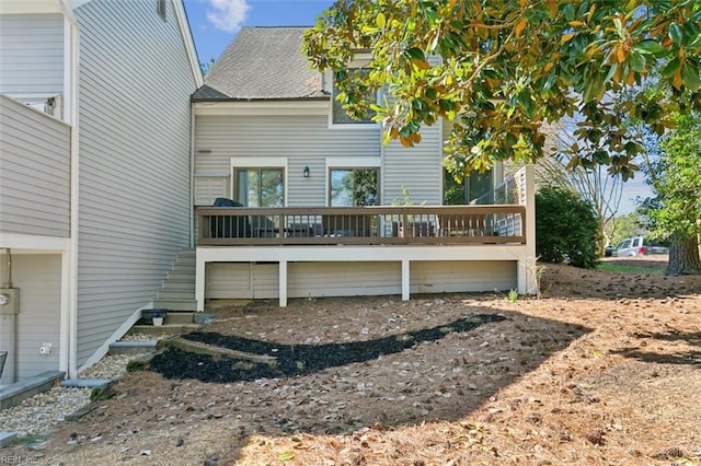 rear view of house featuring a shingled roof, stairway, and a wooden deck