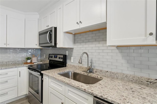 kitchen with tasteful backsplash, appliances with stainless steel finishes, white cabinets, and a sink