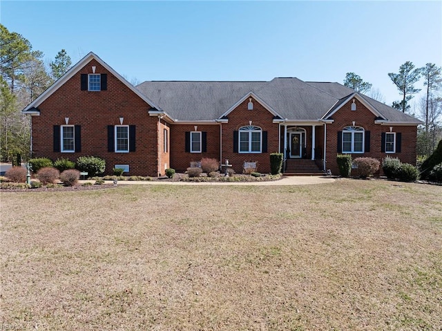 view of front of house featuring brick siding, a shingled roof, and a front yard