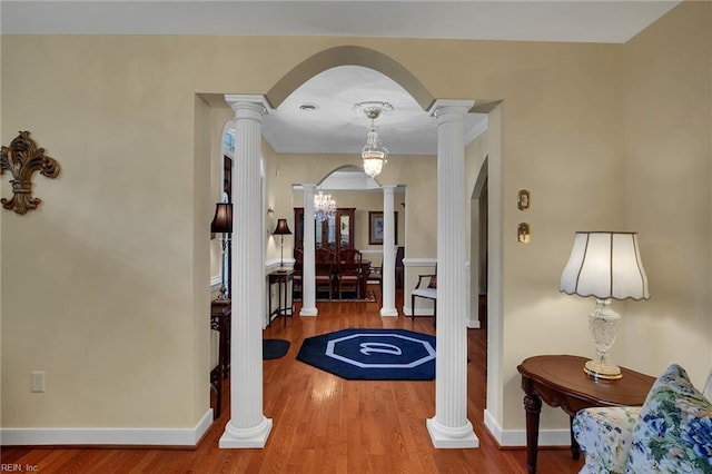 foyer with wood finished floors, arched walkways, and ornate columns