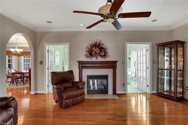 living room featuring visible vents, arched walkways, wood finished floors, and crown molding