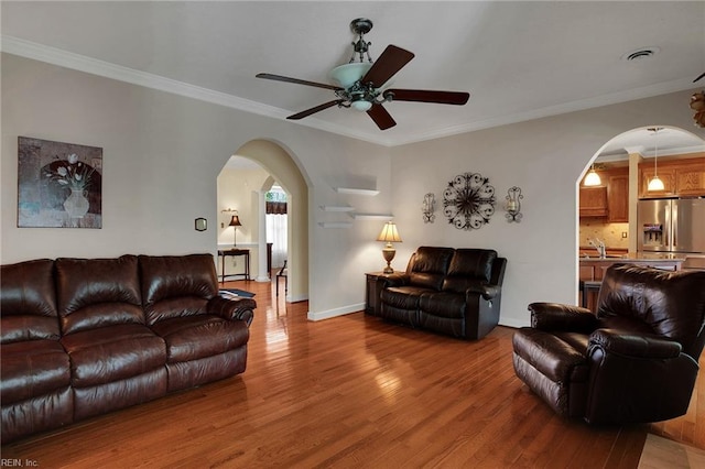 living area featuring visible vents, wood finished floors, arched walkways, crown molding, and ceiling fan