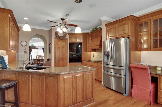 kitchen featuring brown cabinetry, a peninsula, stainless steel fridge with ice dispenser, a sink, and ceiling fan