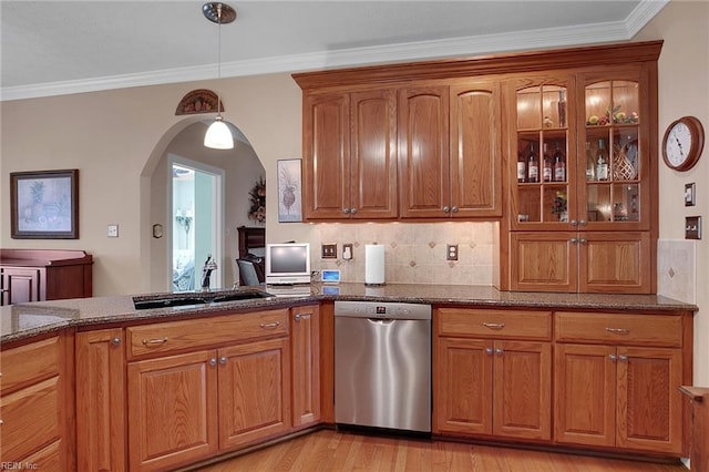 kitchen featuring dark stone countertops, brown cabinetry, arched walkways, glass insert cabinets, and stainless steel dishwasher